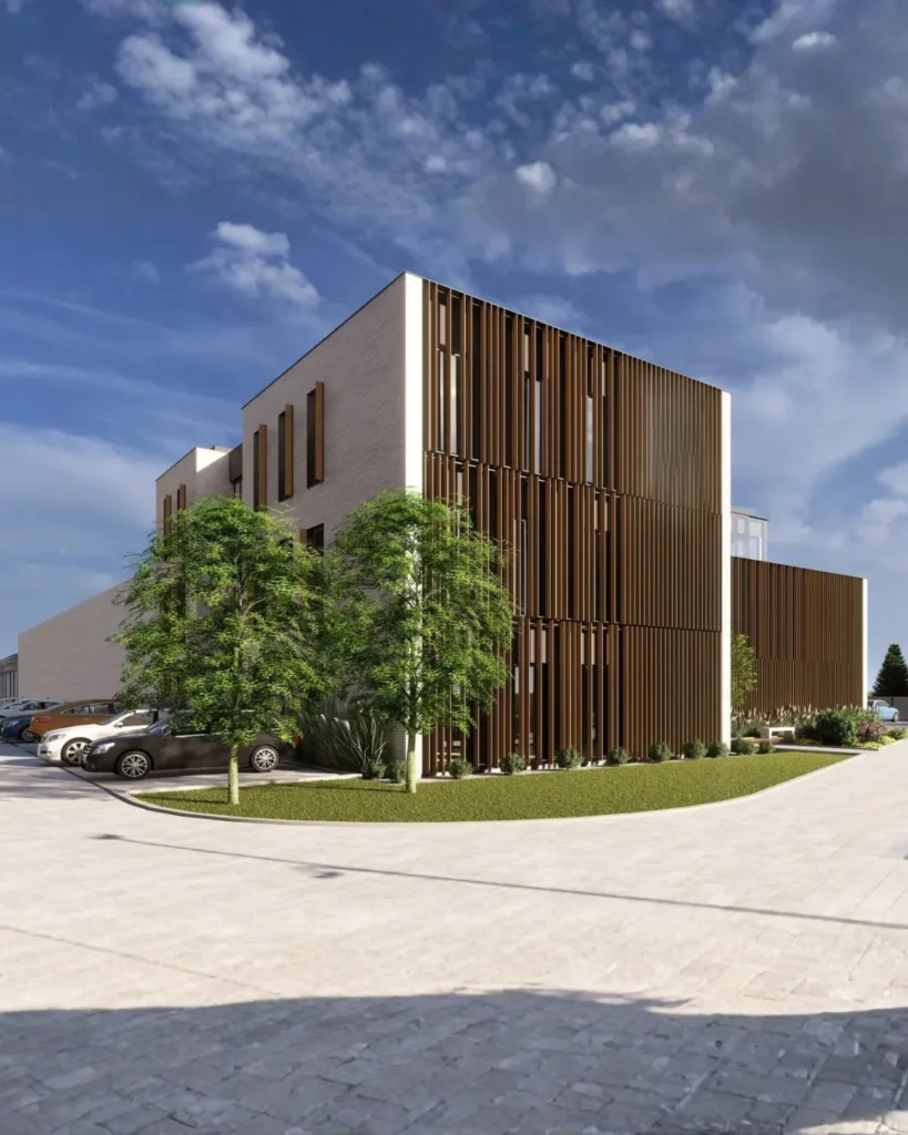 Nowoczesny kompleks biurowo-przemysłowy z elewacją z pionowych lameli, dużymi przeszkleniami i minimalistyczną architekturą. Widok frontowy na reprezentacyjną strefę wejściową, zagospodarowaną zieleń oraz nowoczesną przestrzeń wspólną wokół budynku.
