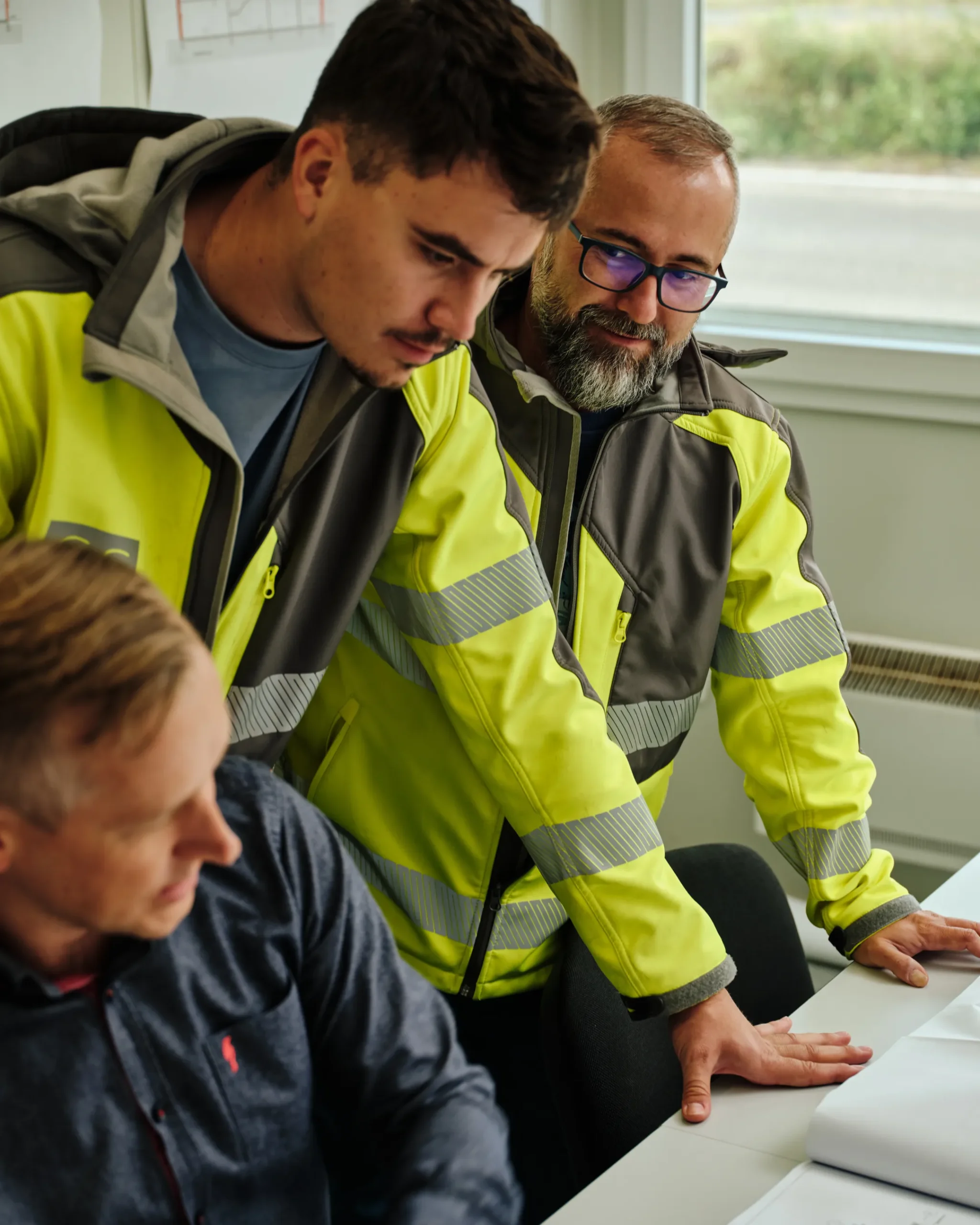 Zespół CS Construction podczas analizy dokumentacji projektowej i koordynacji inwestycji. Inżynierowie omawiają szczegóły realizacji w nowoczesnym biurze projektowym.